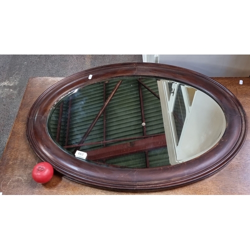 663 - Oval wooden-framed mirror with chain for hanging, from the early 20th century. Rich wood tones and c... 