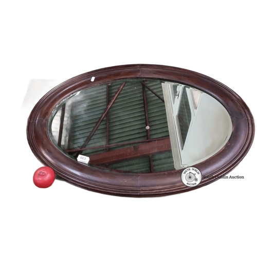 663 - Oval wooden-framed mirror with chain for hanging, from the early 20th century. Rich wood tones and c... 