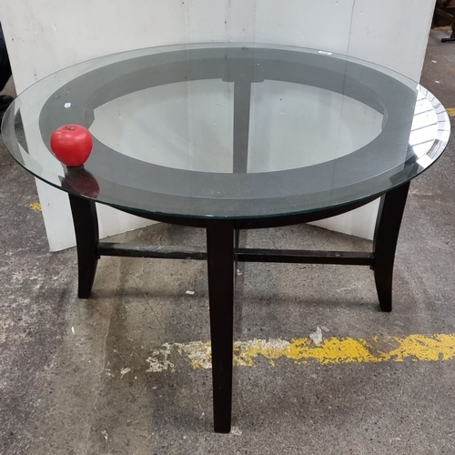 665 - Modern glass-top coffee table with a circular design and black wooden legs.