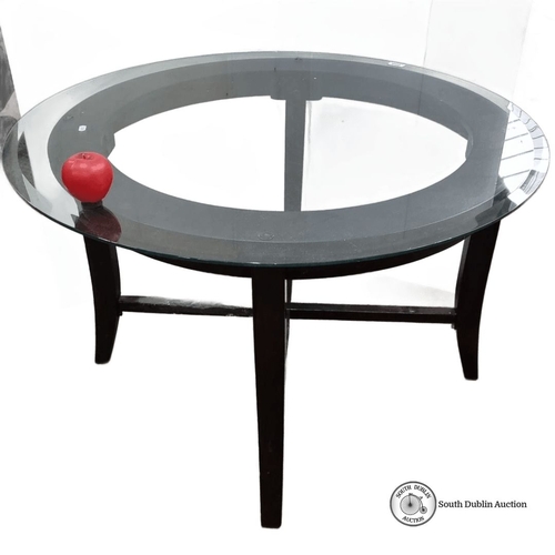 665 - Modern glass-top coffee table with a circular design and black wooden legs.