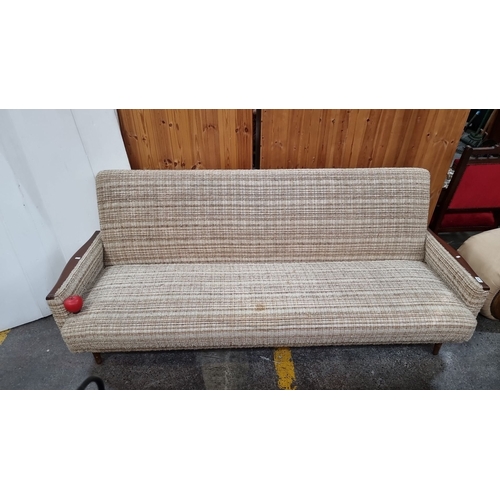 679 - Star Lot : Mid-Century Modern sofa with textured fabric upholstery and wooden armrests, reflecting 1... 