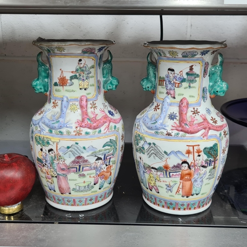 878 - An antique pair of Chinese Qing Dynasty baluster vases in the Famille Rose pattern with twin foo dog... 