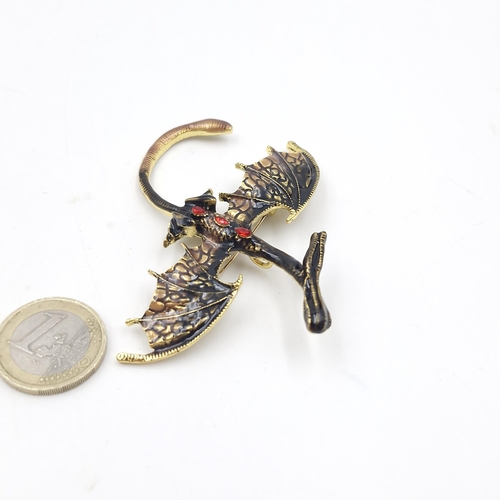 1054 - A Large dragon brooch with brown and gold marking and red gemstones on his back.