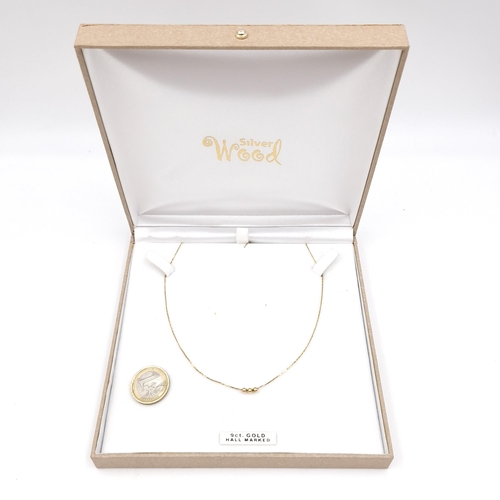 1064 - A pretty 3 ball 9ct gold necklace. 40cm long. 1.33 grams.