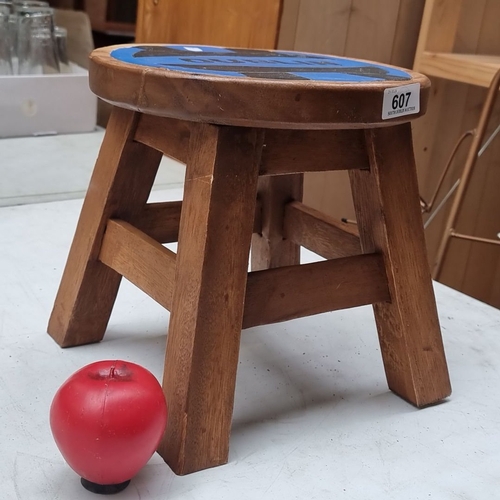 607 - Wooden stool featuring a painted Dublin motif. Compact, rustic design with sturdy legs.