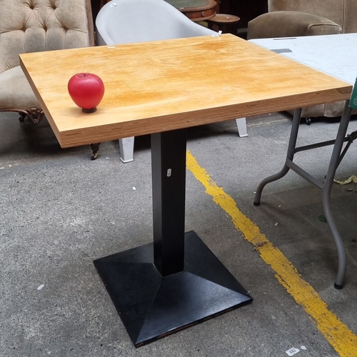 758 - Square commercial  table with light wood top and sturdy black pedestal base.