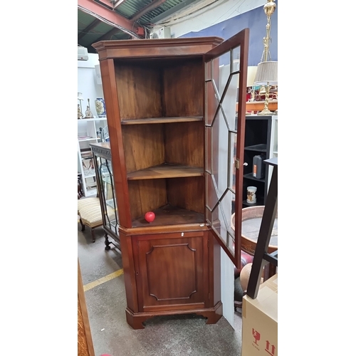 778 - Mahogany corner display cabinet with glazed door, two shelves, and panelled lower door. It's in the ... 