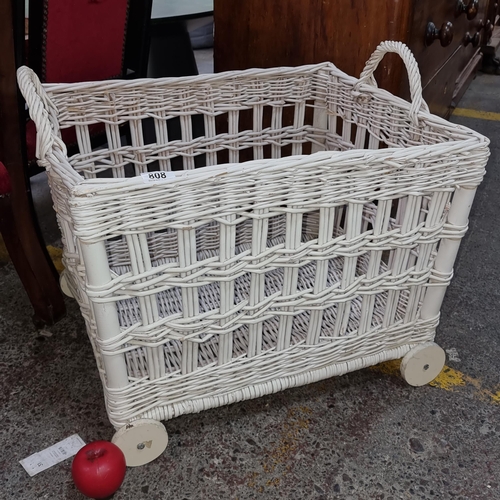 808 - A large wicker basket on wheels in a white painted finish.