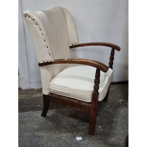 1253 - Upholstered armchair with carved wooden arms and legs, featuring a classic wingback design with crea... 