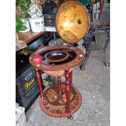 1290 - Bar globe drinks cabinet features a wooden stand, red accent finish, and vintage map design. The hin... 