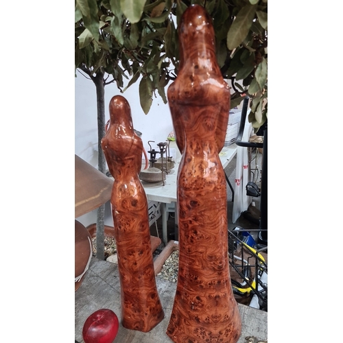 981 - Pair of hand-carved wooden statues, tall and slender, featuring smooth, polished brown wood with int... 