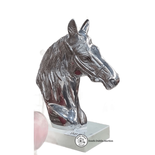 985 - A Silver horse head sculpture on a white base, featuring a polished finish.