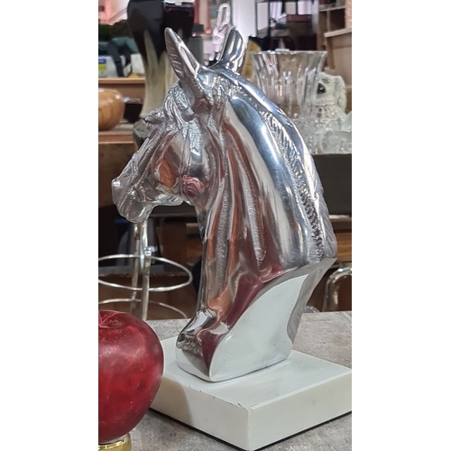 985 - A Silver horse head sculpture on a white base, featuring a polished finish.