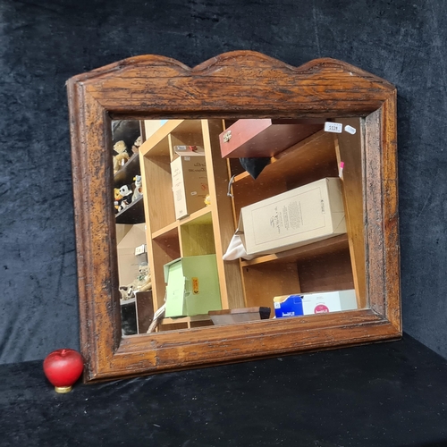 1218 - A large wall hanging mirror. Housed in a heavy wooden thick rustic frame. 
MM:74 x 64cm including fr... 