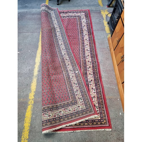 943 - Super Star Lot : A large handmade, hand knotted floor rug dominantly in red featuring a repetitive p... 