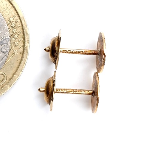 36 - A pair of machine cut nine carat gold stud earrings. Weight - 0.75 grams. Boxed.