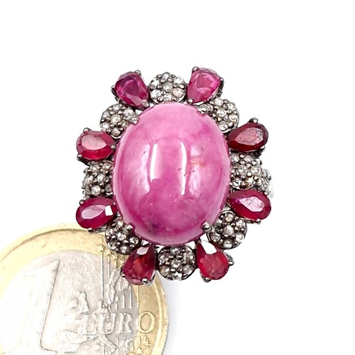 124 - Star Lot : A stunning example of a large Ruby cabochon gemstone ring with diamond and ruby surround ... 