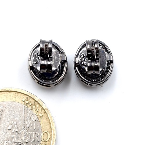 591 - Star Lot : A pair of 4ct oval cut blue sapphire stud earrings with diamond halo set in sterling silv... 