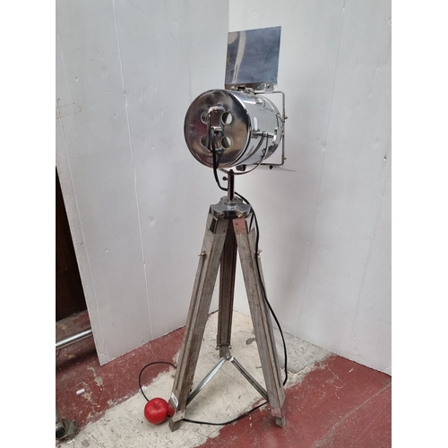 369 - Retro-style tripod spotlight features a chrome body with adjustable barn doors, mounted on a wooden ... 