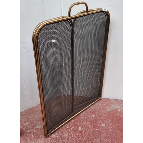 388 - Three-panel brass fireplace screen with mesh inserts, featuring a central handle.