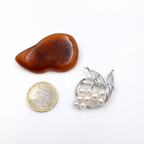 516 - Two brooches - a polished rough amber example together with a floral pearl mounted brooch. Pins inta... 