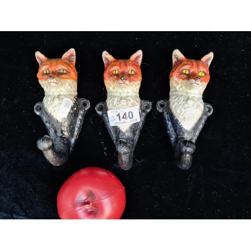 140 - A trio of heavy hand painted cast metal coat hooks in the form of foxes.