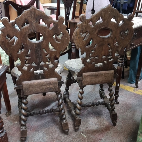 450 - Pair of ornately carved Victorian oak hall chairs, featuring intricate scrollwork and turned legs, c... 