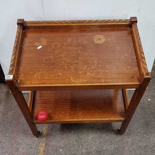 485 - Oak serving trolley with carved rail detailing, featuring two tiers and caster wheels. From mid-cent... 