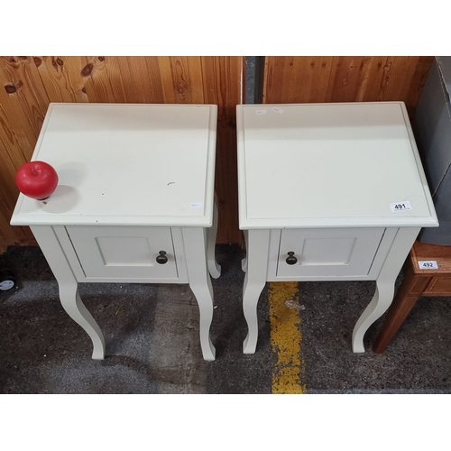 491 - Pair of white wooden bedside tables with single cabinet door, featuring curved legs and a minimalist... 