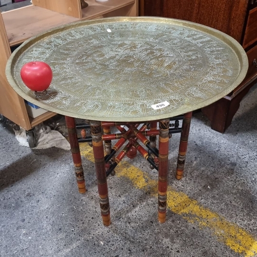 498 - Ornate brass tray table with intricate engravings, supported by an elaborately carved wooden base.