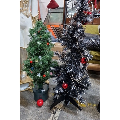 673 - Pair of decorative artificial Christmas trees, one green with colorful ornaments, and one silver wit... 