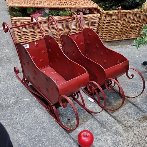 678 - Pair of new decorative red metal sleighs, featuring embossed star details and elegant scrollwork run... 