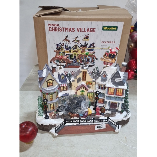 682 - Musical Christmas Village by Woodie's features illuminated houses, moving Santa and reindeer, and fe... 