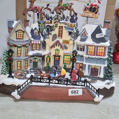 682 - Musical Christmas Village by Woodie's features illuminated houses, moving Santa and reindeer, and fe... 