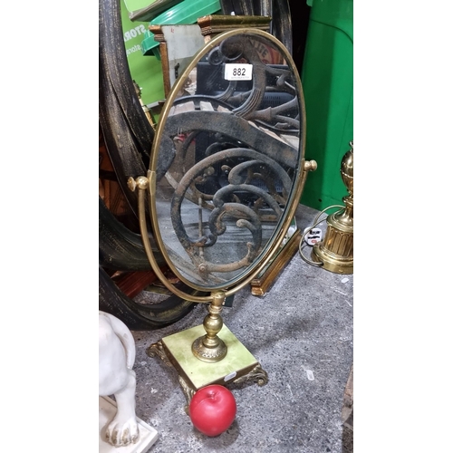 882 - Victorian-style brass vanity mirror with an oval frame and ornate base. Features green felt backing.