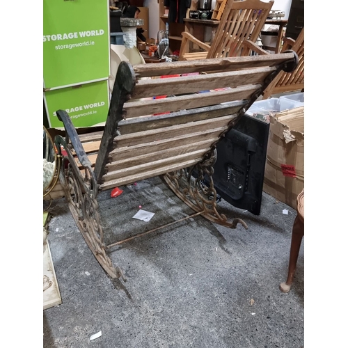 888 - A Wrought iron and wood rocking chair features intricate scrollwork and a slatted seat design.