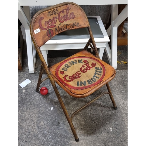 894 - 1985 Coca-Cola folding chair features New Coke branding, a hand-painted design, and a metal frame. I... 