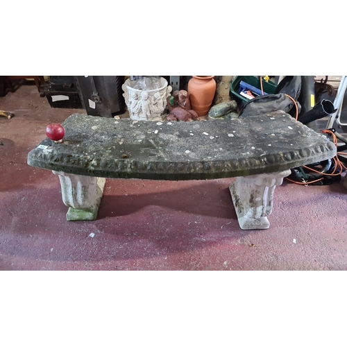 921 - Stone garden bench with carved legs, featuring a textured top surface. Rustic outdoor seat.