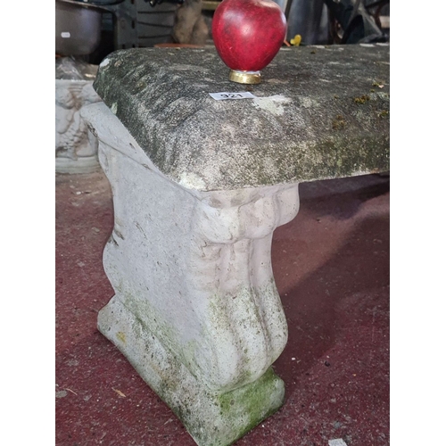 921 - Stone garden bench with carved legs, featuring a textured top surface. Rustic outdoor seat.