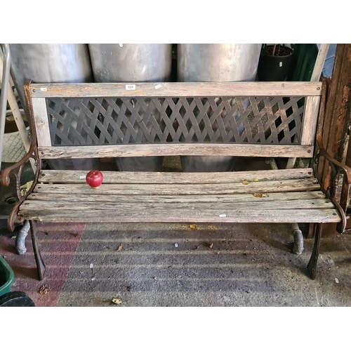 928 - An Ornate garden bench with a wooden slat seat, decorative cast iron arms, and a lattice-patterned b... 