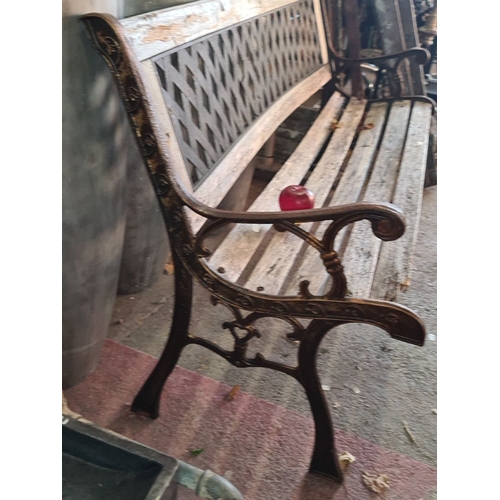 928 - An Ornate garden bench with a wooden slat seat, decorative cast iron arms, and a lattice-patterned b... 