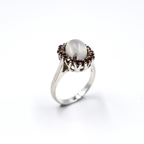 13 - A 925 silver ring with central moonstone with garnet cluster surround. Size - N. Weight - 4.55 grams... 