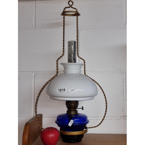 1019 - A gorgeous vintage hanging coolie oil lamp. Features a blue glass reservoir, a milk glass shade and ... 