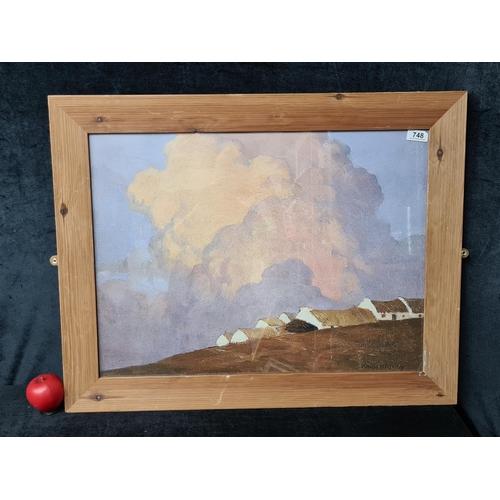 748 - A large print of a Paul Henry painting titled 'Cottages on a Hill'. Housed in a wooden frame behind ... 