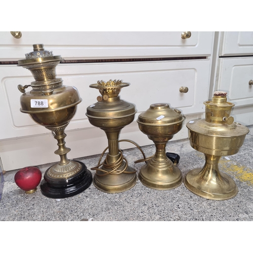 788 - Four antique brass oil lamps. Featuring one tall, highly detailed example mounted on a ceramic base.