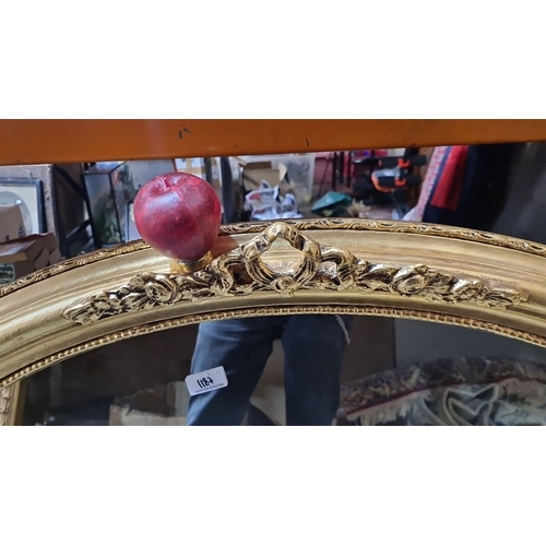 1187 - Star Lot : A large Oval mirror with ornate gold frame and decorative apple accent, featuring intrica... 