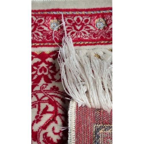 983 - Persian-style rug, featuring intricate red and bone floral patterns with fringe edges.