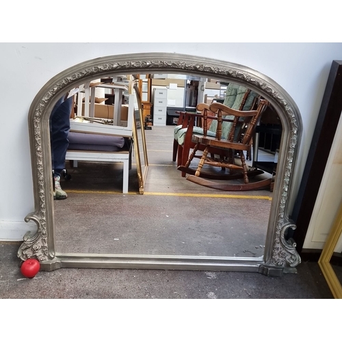 988 - Star Lot : Silver-framed overmantel mirror with ornate floral detailing. From the early 20th century... 