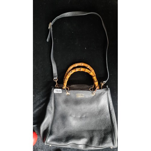 1030 - Star Lot : A fabulous black leather designer handbag by Gucci with glossed bone handles and brass ha... 