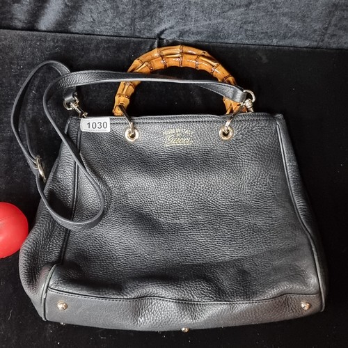 1030 - Star Lot : A fabulous black leather designer handbag by Gucci with glossed bone handles and brass ha... 